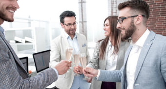 business team raises glasses of champagne in the office 1 e1667459931776 - How to Use Event Technology for Your Corporate Event (Under 100 Employees)